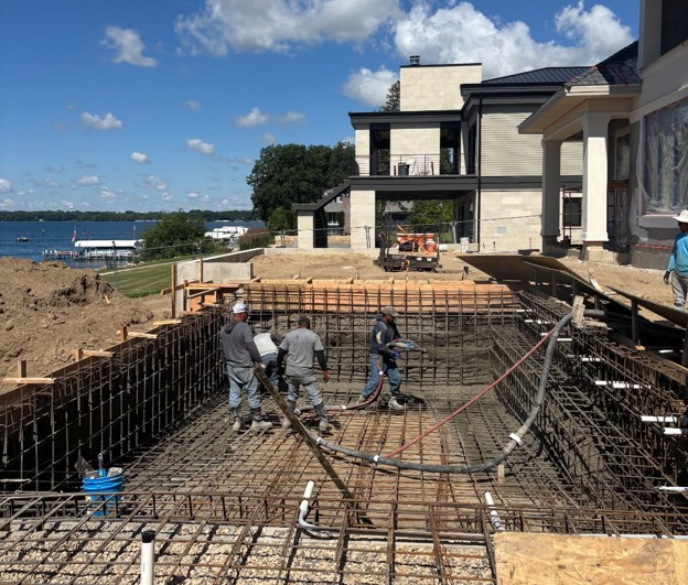 Residential landscape architecture project under construction by Beck Engineering featuring concrete pool installation, site grading, retaining walls, and outdoor living space development at a lakefront home.
